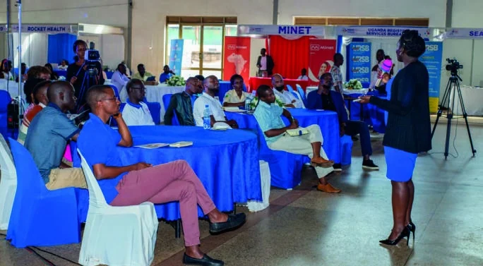 A speaker addresses participants seated around tables during a business session.