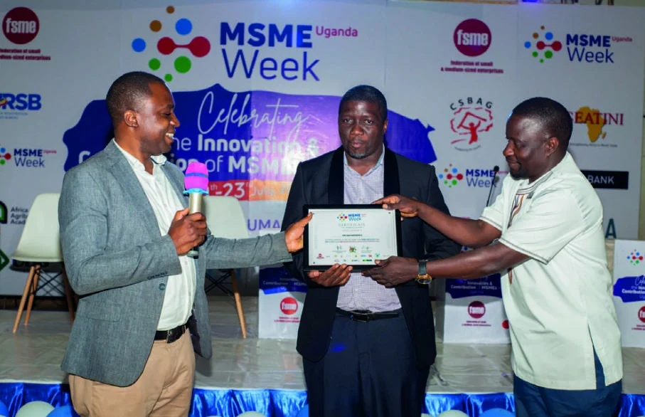 A participant receives a framed certificate on the MSME Week stage.
