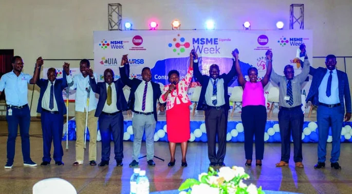 MSME Week participants stand together on stage with their hands raised.